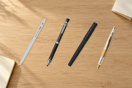 Meşe yazı masasında gri Kokuyo Enpitsu Sharp, siyah Uni Kuru Toga Roulette, mat siyah Pilot Explorer ve gümüş Pentel Kerry Tokai