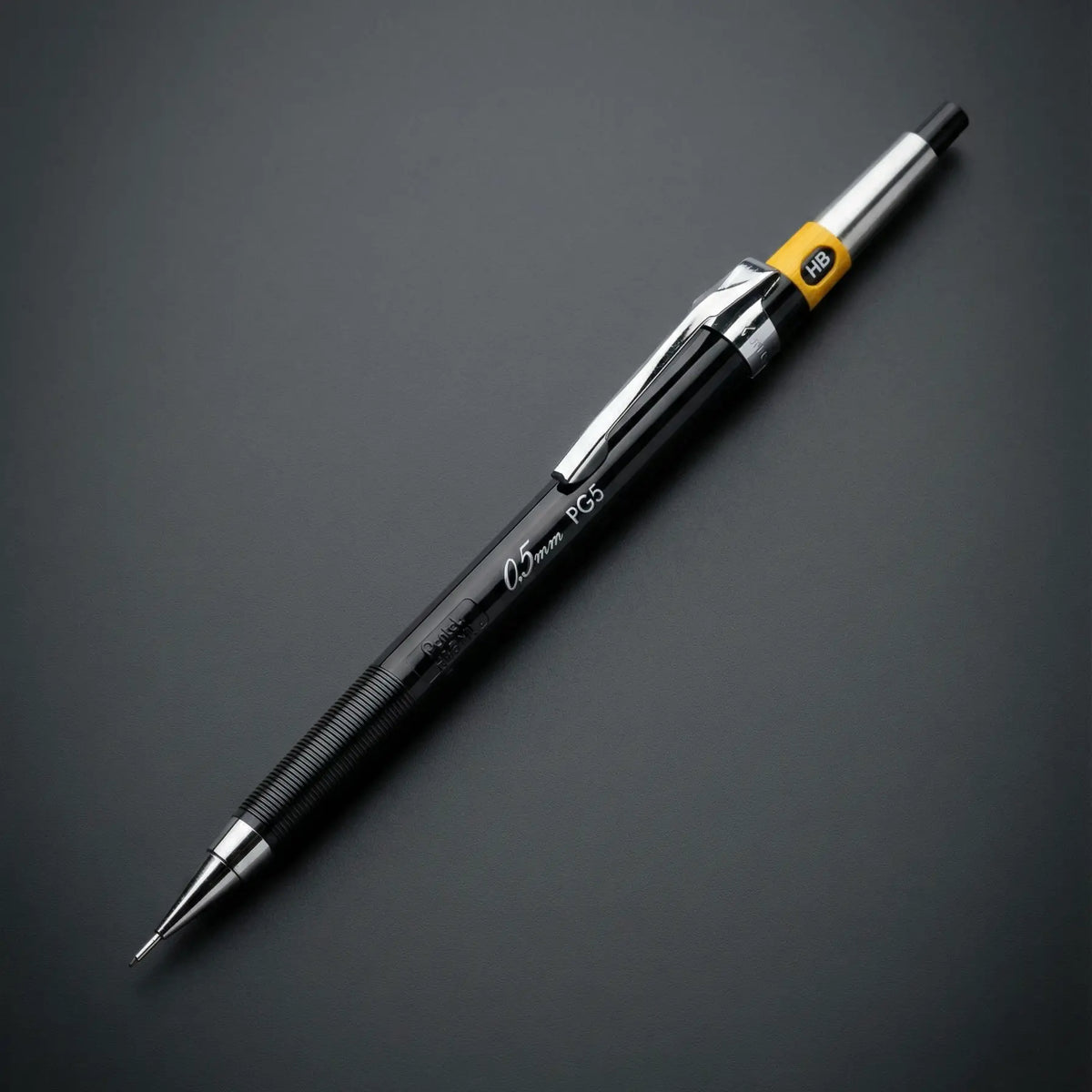 Pentel PG5 versatil kalem siyah gövde ve krom klips, koyu gri zeminde tam boy, 0.5 mm