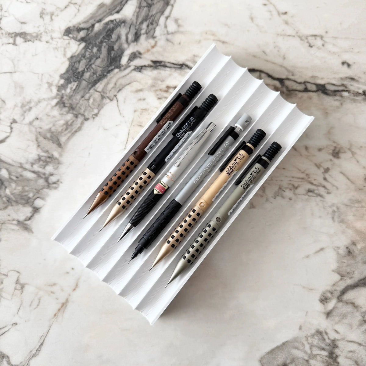 Kalemsy Axis 6'lı kalem tepsisi beyaz, mermer masada altı versatil kalemle dolu