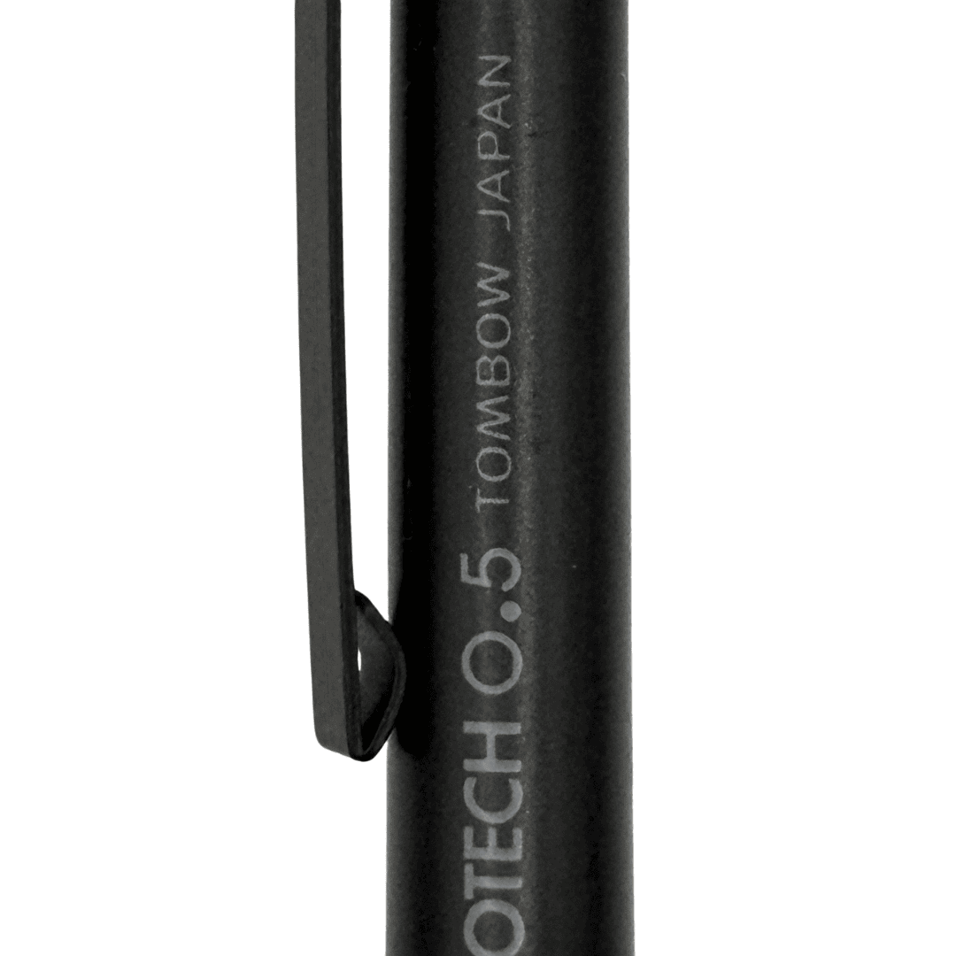 Tombow Monotech 0.5 gövde gravdürü ve ince siyah klips, mat yüzeyde yakın çekim