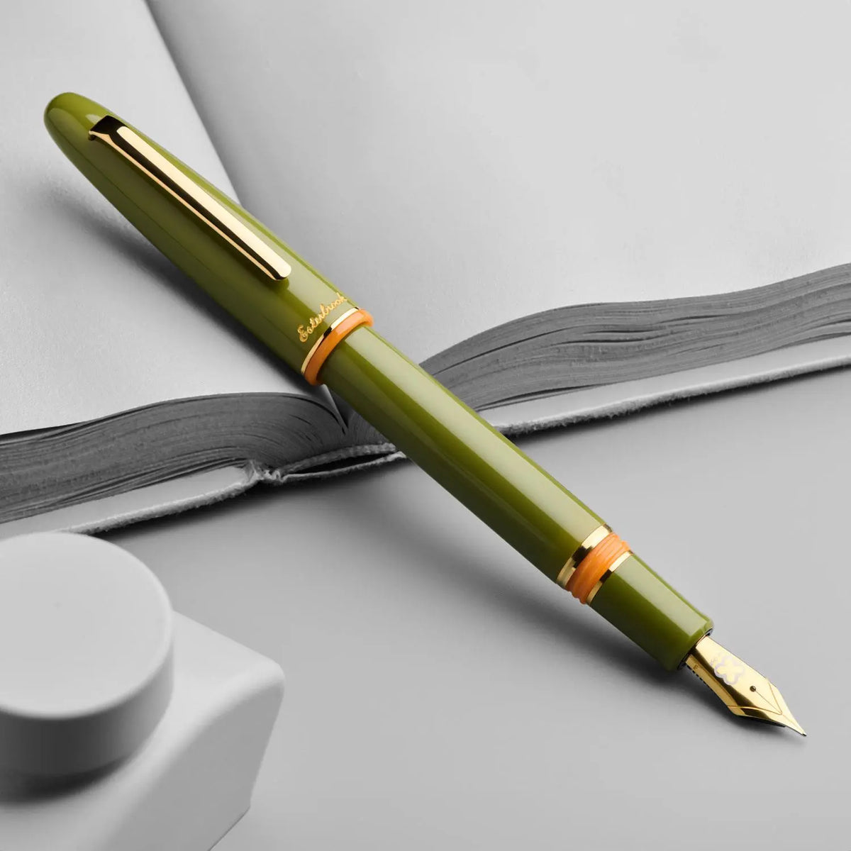 Esterbrook Estie dolma kalem açık defter üzerinde çapraz duruyor, gri kurgu, kapak takılı