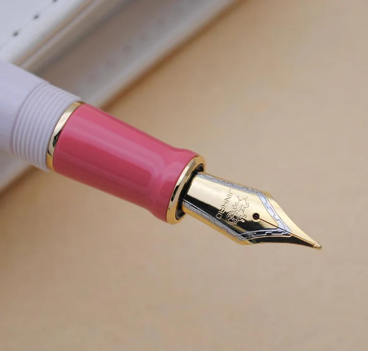 Jinhao 100 dolma kalemin altın rengi medium ucu ve pembe besleme bölümü makro çekim