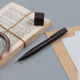 Gentlewood Studio tükenmez kalem koyu kingwood gövde, eski kitap ve büyüteçle masa üstü kurgusu