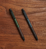 Uni Kuru Toga Wood yeşil ve gri kalem koyu ahşap masa üzerinde yan yana, uçlar açık, 0.5 mm