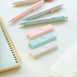 Uni HB kalem ucu kutuları masa üstünde, yanında pastel renkli kalemler ve spiralli defter