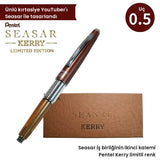 Pentel Kerry Seasar limitli seri versatil kalem, kahve mat kapak ve bal rengi yarı saydam gövde, özel kutusunun önünde