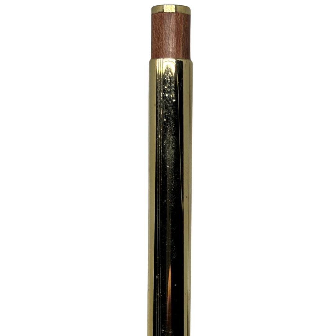Tombow Exta Deluxe kalemin parlak altın rengi üst gövdesi ve ahşap tıklama başlığı, önden yakın çekim