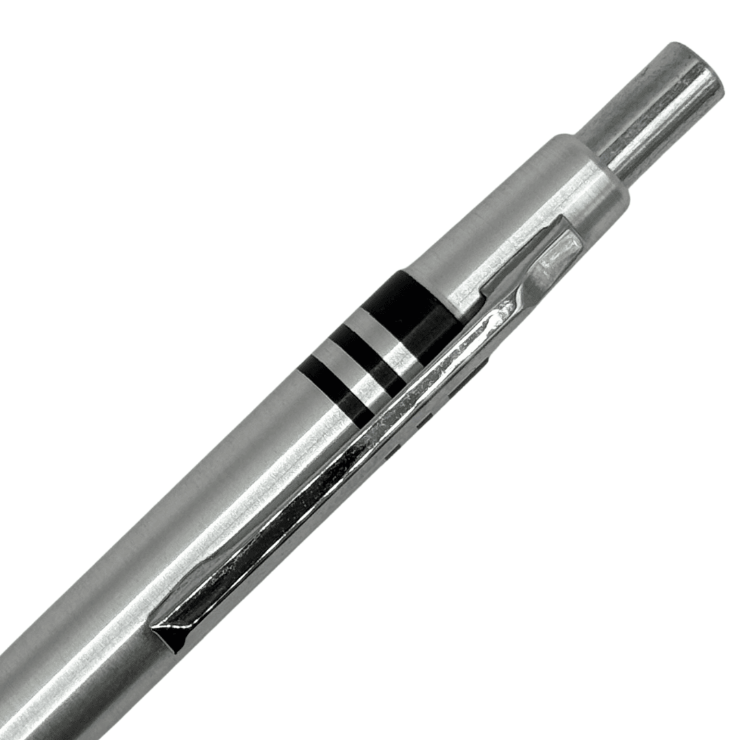 Tombow W kaleminin çelik üst gövdesi, iki siyah halka ve tıklama başlığı yakın çekim