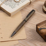 Gentlewood Studio ahşap gövdeli tükenmez kalem, kraft bloknot ve kitapla ahşap masa üstünde